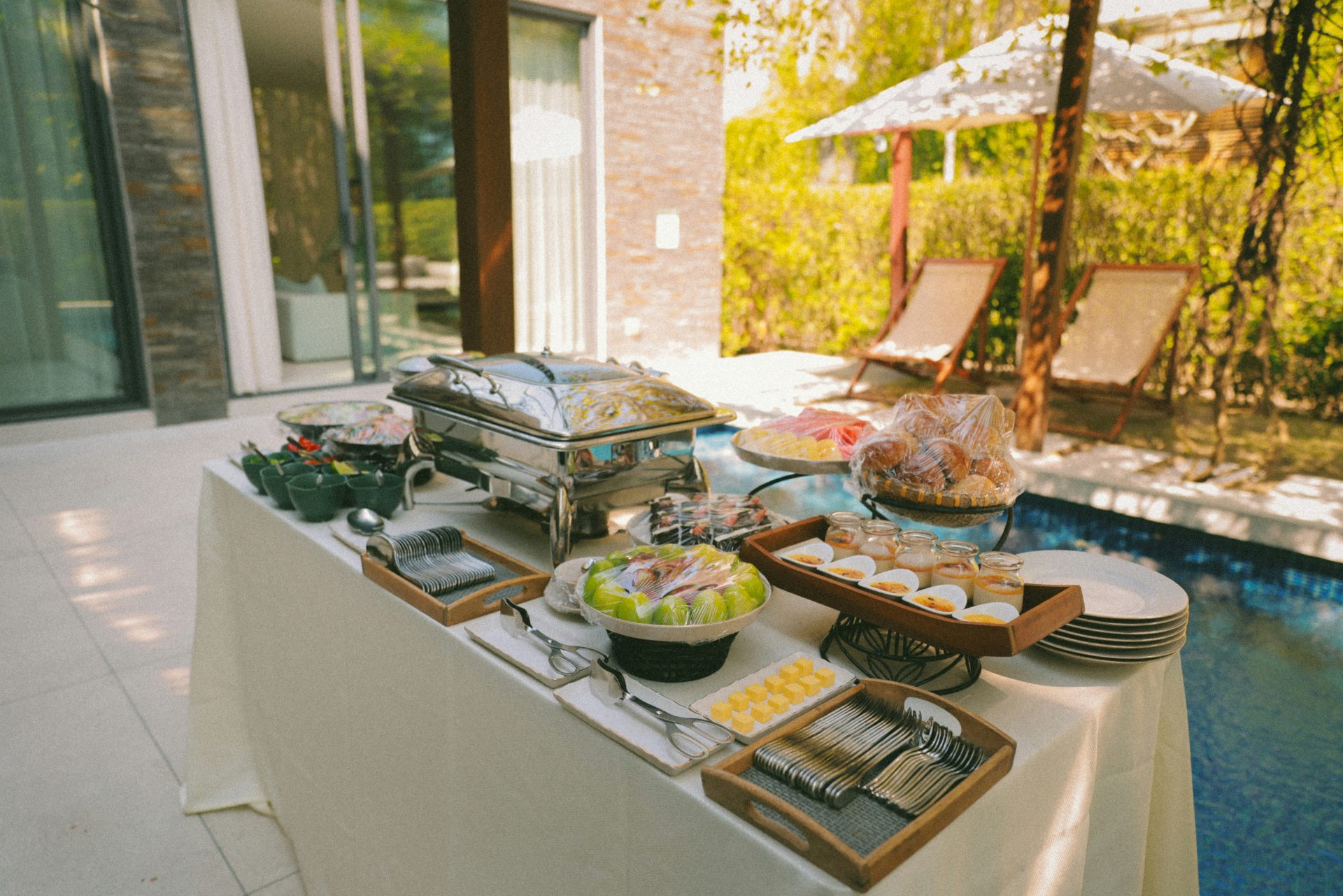 Buffet table with food and drinks by the pool