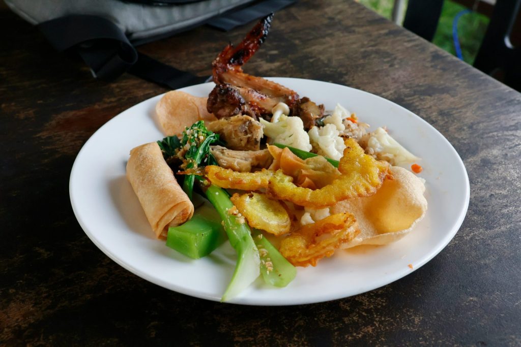 A plate of assorted food including spring rolls and vegetables